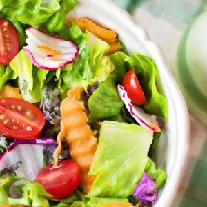 Colorful fresh vegetable salad with cherry tomatoes in a white bowl.