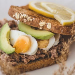 Delicious homemade tuna sandwich with avocado slices and boiled egg on wheat bread.